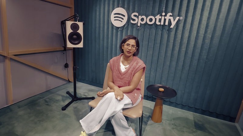 Woman sitting in a Spotify studio with logo displayed on the wall