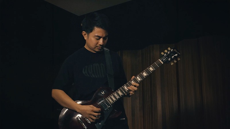 Man playing electric guitar in a dimly lit room